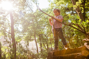 Little boy playing with some sticks in the forest.