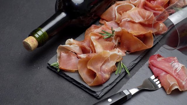 sliced prosciutto or jamon meat and wine on concrete background