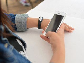 Close-up portrait of a girl using a fitness tracker or heart rate monitor. View the number of steps per day. Fitness concept. A woman looks at the results of training on a fitness bracelet.