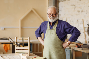 cheerful senior citizen is ready to work in the workshop. hardworking grandpa in the home workshop