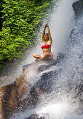 young attractive and happy 30s woman with fit body practicing yoga wet under tropical paradise waterfall stream in meditation and relaxation