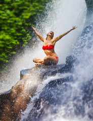 young attractive and happy woman with fit body practicing yoga wet under tropical paradise waterfall stream screaming excited with opened arms
