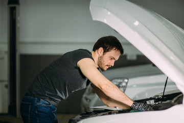 mechanic working in car hood in garage
