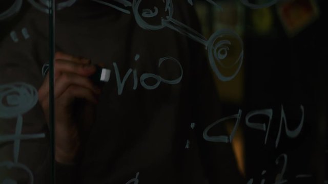 Close-up of a Man Writing Formulas on a Glass Whiteboard. Stock. Close-up of a scientist writing on the glass formula