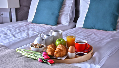 Breakfast on tray in bed in hotel room