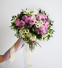 Beautiful woman hands hold bouquet of chrysanthemum flowers yellow and purple on white 