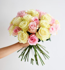 Beautiful woman hand hold bouquet of yellow and pink roses  flowers on white