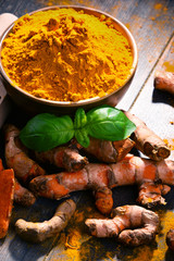 Composition with bowl of turmeric powder on wooden table