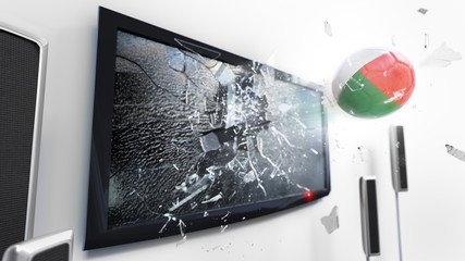 Soccer ball with the flag of Madagascar kicked through a shattering tv screen.(3D rendering series)