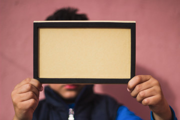 Little boy holding cardboard against wall