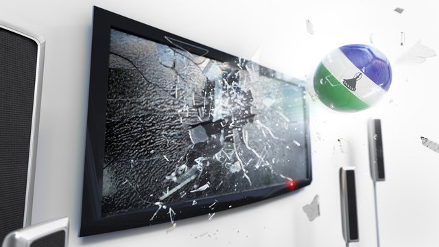 Soccer ball with the flag of Lesotho kicked through a shattering tv screen.(3D rendering series)