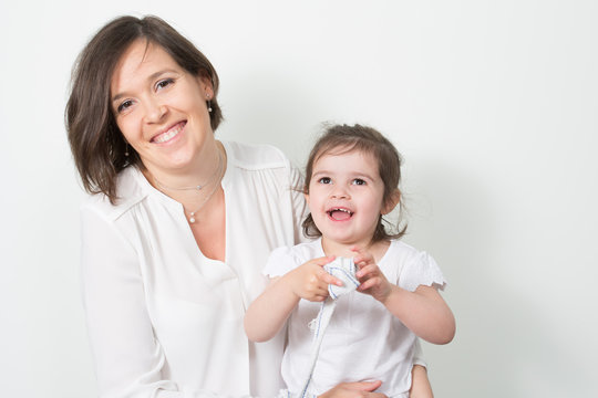 Mother smiling with her daughter against white background