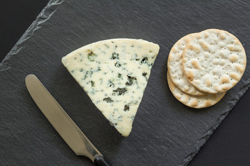 Rochefort cheese and crackers close up top view on black slate board