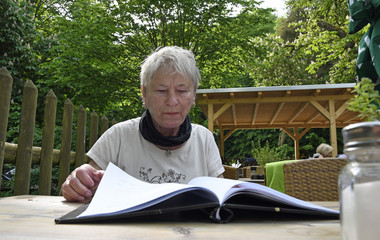 seniorin blättert im gartenlokal in der speisekarte