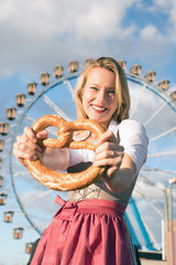 young sexy woman is doing oktoberfest in munic summer, spring folk festival she is wearing a dirndl and holding a hear brezn in her hand