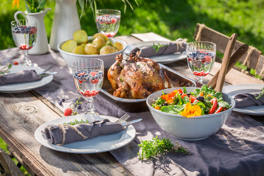 Table in garden with salad and chicken served in summer