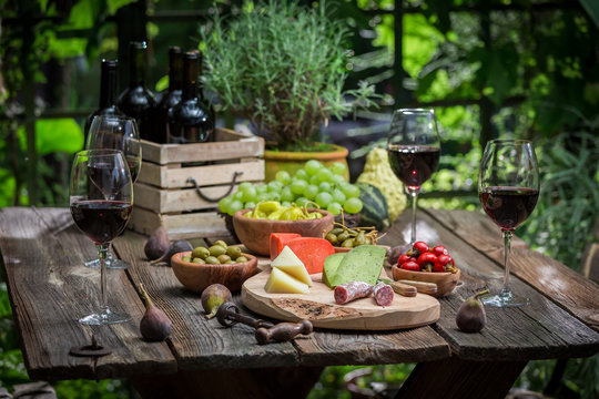 Garden table with snacks, wine and fruits in the evening