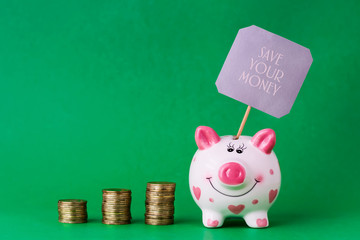 Piggy bank and towers coins. The inscription Save your money. Copy space.