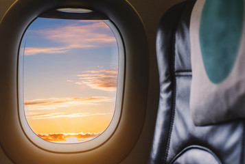 Fototapeta premium Travelling by air plane, looking through plane window enjoying beautiful sunrise from aerial view