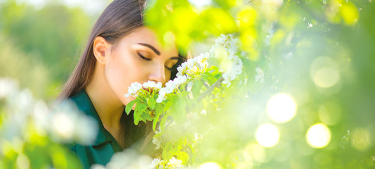 Beauty young woman enjoying nature in spring apple orchard, Happy beautiful girl in a garden with blooming fruit trees - obrazy, fototapety, plakaty
