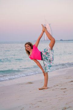 Cute young girl doing yoga at the beach