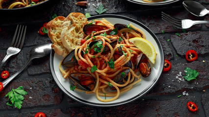 Homemade Pasta Spaghetti with mussels, tomato sauce, chilli and parsley on rustic background. sea food meal