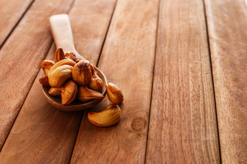 Fried cashew nuts in a wood spoon on a  wooden floor