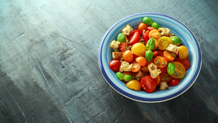 Panzanella Tomato salad with red, yellow, orange cherry tomatoes, capers, basil and ciabatta croutons. summer healthy food.