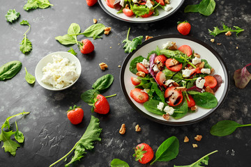 Fototapeta na wymiar Summer Fruit Strawberry, spinach Salad with walnut, feta cheese balsamic vinegar, kale. in a plate. concepts health food