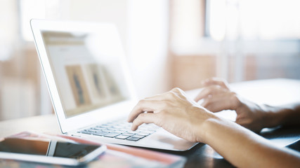 Fototapeta premium Female hands on an aluminum laptop keyboard typing working at home cafe woman writing typing on the keyboard in the open space in the afternoon