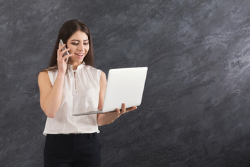 Naklejka premium Woman talking on phone and holding laptop