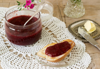 Strawberry jam in a glass jar and toast with butter and jam. Rustic style.