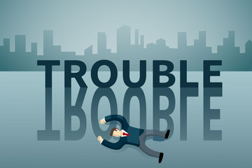 business man lie down on the floor in front of TROUBLE word.