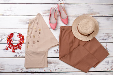 Flat lay female classic clothes. Elegant women trousers and hat on wooden background. Set of feminine clothes and accessories.