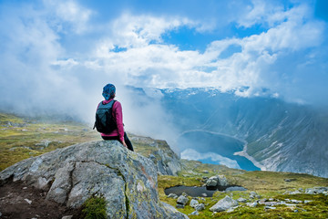 Young woman with backpack standing on fjord coast