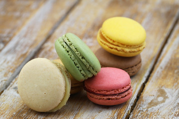 Colorful crunchy macaroons stacked up on rustic wooden surface with copy space
