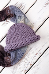 Women scarf and hat on wooden background. Fashion winter accessories for women, top view.
