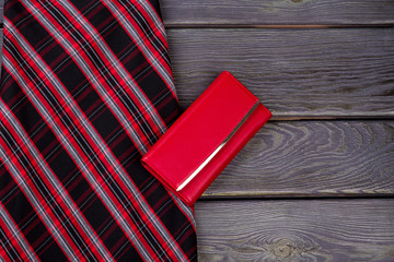 Female elegant clothes on wooden background. Women black striped skirt and red leather purse, copy space.