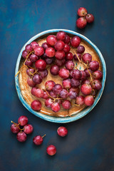 Red grapes on a rustic dish, blue background. Top view, vertical frame.