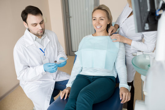 Crop assistant preparing cheerful girl while dentist getting special clean tools from bag. 