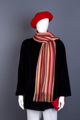 Red beret, scarf and black coat. Female mannequin with black clothes and red accessories. Women autumn casual outfit.