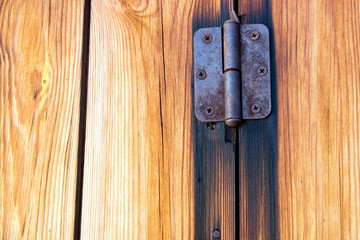 Rusty hinge on an old wooden door in the summer in the village