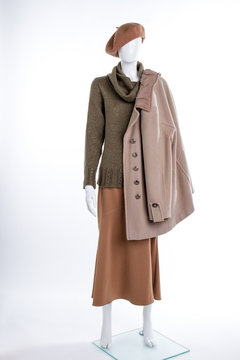 Female beret and coat on mannequin. Female mannequin with beret, sweater, skirt and overcoat. Female autumn outfit.