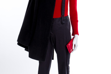 Black coat, trousers and red wallet. Close up red female sweater, black trousers and overcoat. Autumn outfit shop.