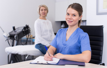 Obraz premium Cosmetologist recording examination results of mature female