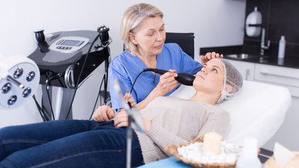 Beautician with client during hardware facial procedure