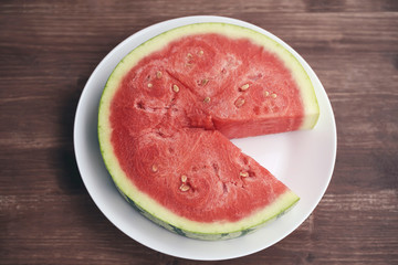 large cut piece of red juicy fresh watermelon is appetizingly lying on a white plate.