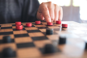 Closeup image of people playing and moving checkers in a chessboard