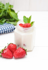 Cream with a strawberry on white wooden background. 
