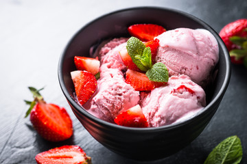 Strawberry ice cream with fresh berries on black.